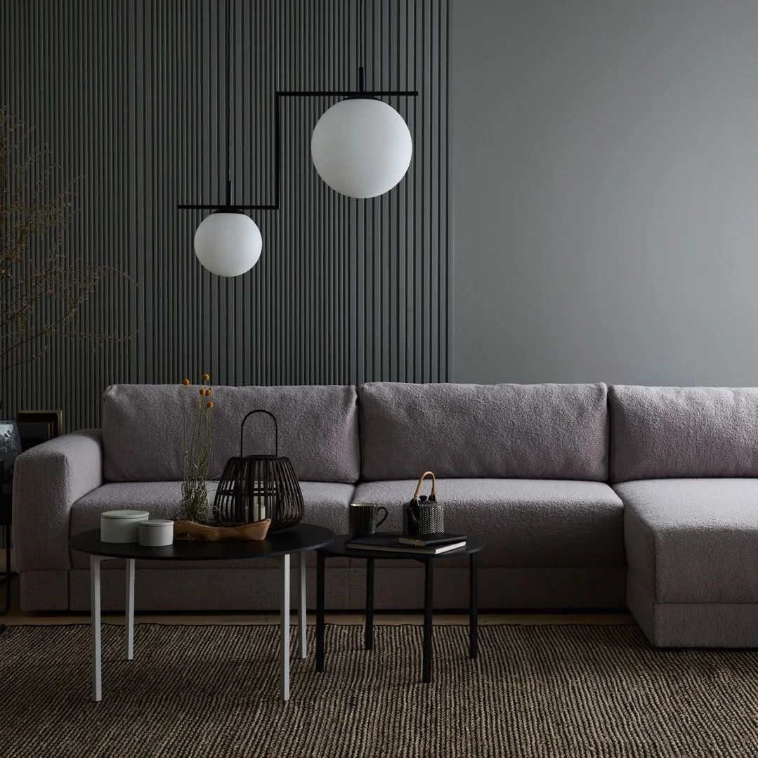 Minimalistyczna szara sofa w eleganckim, ciemnym wnętrzu.